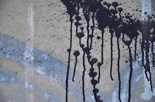 une photographie d'un gros plan de taches de peinture noire sur un mur de béton. verser de la peinture sur le mur dans un ordre aléatoire. le concept de graffiti et de culture street art photo