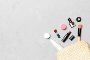 vue de dessus des produits de maquillage tombés du sac de cosmétiques sur fond de ciment. concept cosmétique avec espace pour votre conception photo