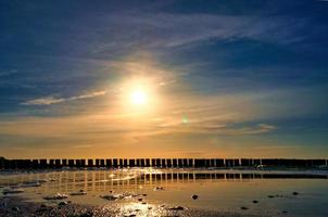 les épis s'avancent dans la mer au coucher du soleil. le soleil brille sur la mer baltique. paysage photo