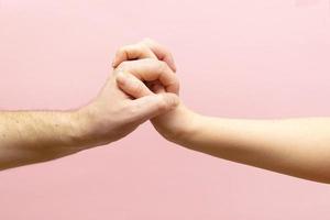 jeune femme et homme main dans la main ensemble sur fond rose. photo