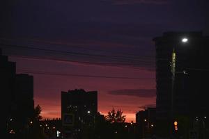 coucher de soleil rose vif et voitures sur la route. toits des maisons et un coucher de soleil lumineux. photo