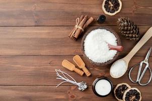 ingrédients pour la fabrication de bougies, flocons de cire de soja, bougies, mèches de cannelle et cuillères en bois sur fond de bois photo