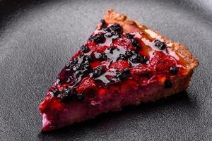 délicieuse tarte fraîche aux framboises et autres baies et fromage sur une assiette sombre photo