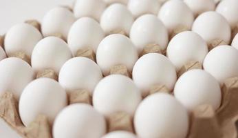 gros plan d'œufs de poule crus dans un bac à œufs en papier. groupe d'œufs blancs frais dans une cassette en carton. aliments biologiques de la nature bons pour la santé.