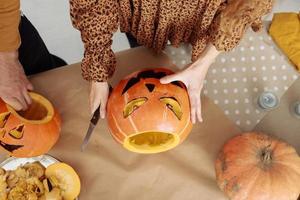 Joyeux Halloween. famille mère père et enfant fille coupent une citrouille pour des vacances à la maison. photo