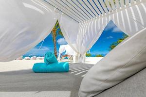 incroyable scène de plage tropicale avec auvent blanc et rideau pour un concept de détente d'été de luxe. ciel bleu avec du sable blanc pour fond de paysage de plage ensoleillée et vacances d'été ou conception de vacances photo