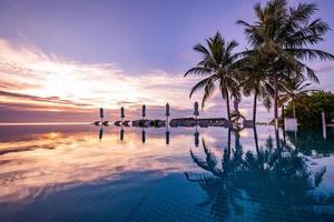 piscine de luxe sur la plage, scène tranquille de paysage tropical exotique avec espace de copie, fond d'été pour les vacances. beau ciel au bord de la piscine et au coucher du soleil. plage tropicale luxueuse photo