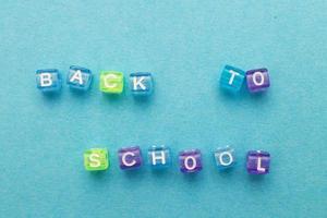 l'inscription de retour à l'école faite de cubes en plastique multicolores sur fond bleu. photo