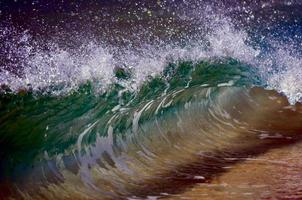 une vague se brisant sur le rivage de sable photo