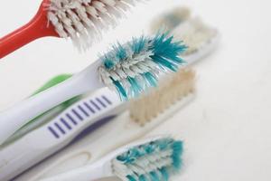 Un tas de vieilles brosses à dents usées avec des poils courbés sur un fond blanc photo