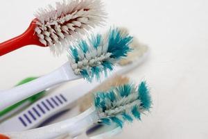 Un tas de vieilles brosses à dents usées avec des poils courbés sur un fond blanc photo