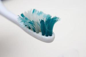 Une vieille brosse à dents usée avec des poils courbés sur un fond blanc photo