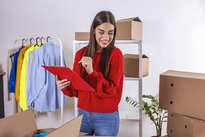 Commencez. jeune femme tenant un presse-papiers après une nouvelle commande du client. boîtes de colis de livraison, propriétaire de petite entreprise travaillant au bureau à domicile, concept d'achat en ligne photo