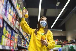 jeune avec masque protecteur achetant des produits d'épicerie dans le supermarché.préparation à une quarantaine pandémique due à l'épidémie de coronavirus covid-19. photo