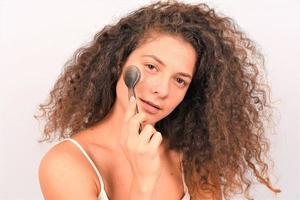 profiter d'une femme charmante avec une brosse spéciale pour un nettoyage en profondeur du visage enlever le maquillage photo