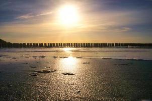 les épis s'avancent dans la mer au coucher du soleil. le soleil brille sur la mer baltique. paysage photo