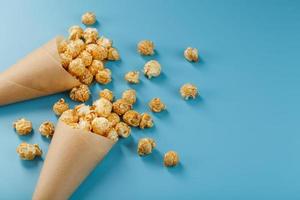 pop-corn au caramel dans une enveloppe en papier sur fond bleu. photo