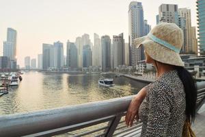 dubai, eau, 2022 - belle femme touristique caucasienne en robe d'été à la mode profitez de la marina de dubai aux émirats arabes unis. saison touristique de luxe et de confort photo