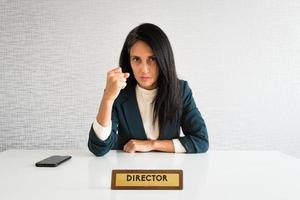 jeune femme d'affaires brune caucasienne mignonne directrice au bureau montre le poing à la caméra au travail pour l'employé plein de ressentiment en colère regard sérieux à la caméra. employé point de vue photo