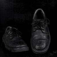 paire de chaussures classiques masculines noires sur fond noir. chaussures poussiéreuses photo