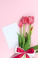 tulipes avec papier pour texte sur fond rose. vacances, 8 mars, anniversaire, fête internationale de la femme, de la fête des mères et de la saint valentin. copie espace photo