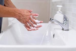 les mains de la personne se lavent avec des bulles de savon et rincent à l'eau claire pour prévenir et arrêter la propagation des germes, virus ou covid-19. bonne santé et bonne hygiène photo