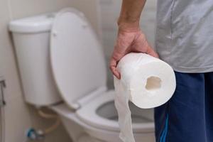 l'homme debout a la diarrhée et des aliments très toxiques. l'homme touche le ventre dans la salle de bain. douleur abdominale, diarrhée, concept de cancer du côlon photo