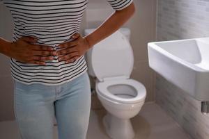 les femmes ayant des problèmes de cystite devant la cuvette des toilettes manipulent le ventre veulent faire pipi, concept d'incontinence photo