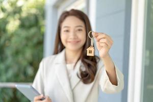 bail, location et vente de maison. le directeur de l'agent immobilier sourit en tenant la clé pour le nouveau propriétaire. location maison, vente, prêt crédit financier, assurance, vendeur, marchand, versement, acheter, vendre, emménager photo