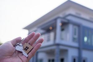le propriétaire détient une nouvelle clé de maison d'un courtier immobilier. maison à vendre et à louer concept. photo