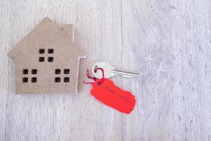 clé et papier déchiré rouge avec message de vente de maison sur fond en bois. concept de vente à domicile