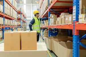 le directeur d'usine masculin asiatique inspecte les marchandises dans l'entrepôt ou l'inventaire et vérifie le produit en stock. transport logistique expédition, livraison aux clients par l'intermédiaire d'une société de transport. inspection photo