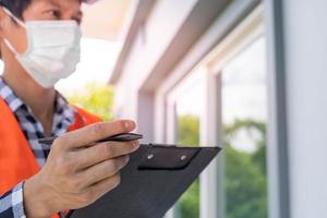 un inspecteur ou un ingénieur inspecte et inspecte un bâtiment ou une maison à l'aide d'une liste de contrôle. ingénieurs et architectes travaillent à la construction de la maison avant de la remettre au propriétaire. photo