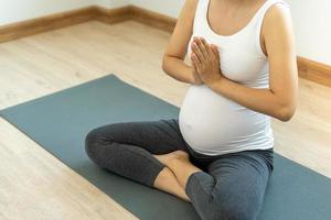 la mère enceinte fait du yoga à la maison pour une bonne santé. les femmes enceintes font de l'exercice et pratiquent la méditation pour se détendre. concept de yoga et de remise en forme de grossesse. photo