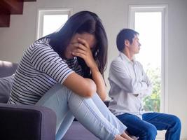 un couple asiatique a de sérieux problèmes de querelle assis sur le canapé à l'intérieur de la maison. la femme s'inclina tristement. le mari a tourné le dos après un conflit. photo