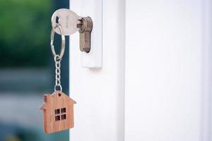 une clé de maison avec un porte-clés inséré dans la serrure de la porte. acheter un nouveau concept de maison.