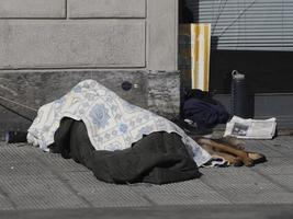 un sans-abri dormant sur un lieu public avec un chien photo