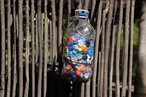 bouteilles gobelets à recycler. grand gallon en plastique plein de bouteilles colorées tasses journée ensoleillée. photo
