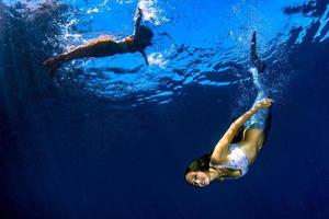 deux sirènes nageant sous l'eau dans la mer d'un bleu profond photo