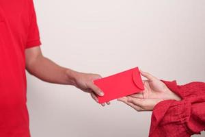 les gens donnent à la main une enveloppe rouge chinoise, un cadeau en argent pour les vacances du nouvel an lunaire photo