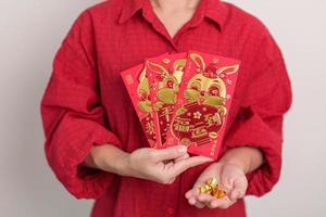 femme tenant une enveloppe rouge chinoise avec des lingots d'or, cadeau d'argent pour les vacances de bonne année lunaire. phrase chinoise signifie bonheur, en bonne santé, chanceux et riche photo