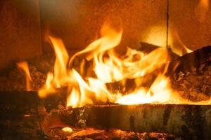 le bois de chauffage brûle dans la fournaise du gros plan du foyer. chauffage alternatif respectueux de l'environnement, pièce chaleureuse et confortable à la maison, combustion du bois photo
