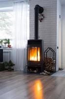 poêle noir, cheminée à l'intérieur de la maison de style loft. chauffage alternatif respectueux de l'environnement, pièce chaleureuse et confortable à la maison, combustion du bois photo