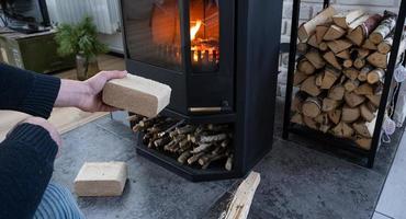 les mains allument le foyer avec des briquettes économiques. briquettes de combustible en sciure de bois pressée pour allumer le four - combustible écologique alternatif économique pour la cheminée de la maison. photo