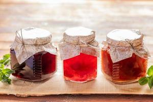 gros plan trois bocaux en verre avec de la confiture maison sont alignés sur fond de bois. photo