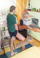 homme mûr essayant de faire du yoga asana à la recherche d'un écran d'ordinateur dans une pièce ensoleillée à la maison. sport à distance. superposition légère. photo