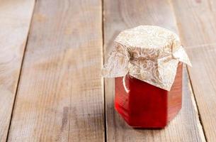 bocal en verre avec confiture de fraises sur une vieille table en bois rustique. photo