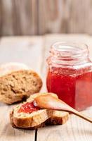 toasts avec confiture de fraises, cuillère en bois, pot de confiture en verre sur table en bois rustique. photo