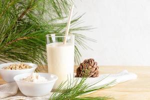 lait de cèdre végétalien en verre et ingrédients pour la cuisson de la farine et des noix sur une table en bois. espace de copie. photo