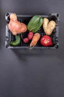 légumes laids mûrs frais dans une boîte en plastique sur fond gris foncé. photo